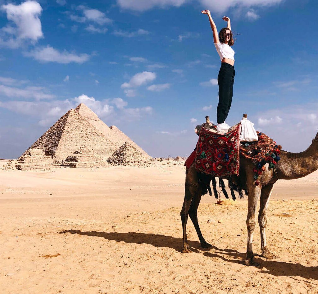 great-shot-of-a-female-tourist-standing-on-a-camel